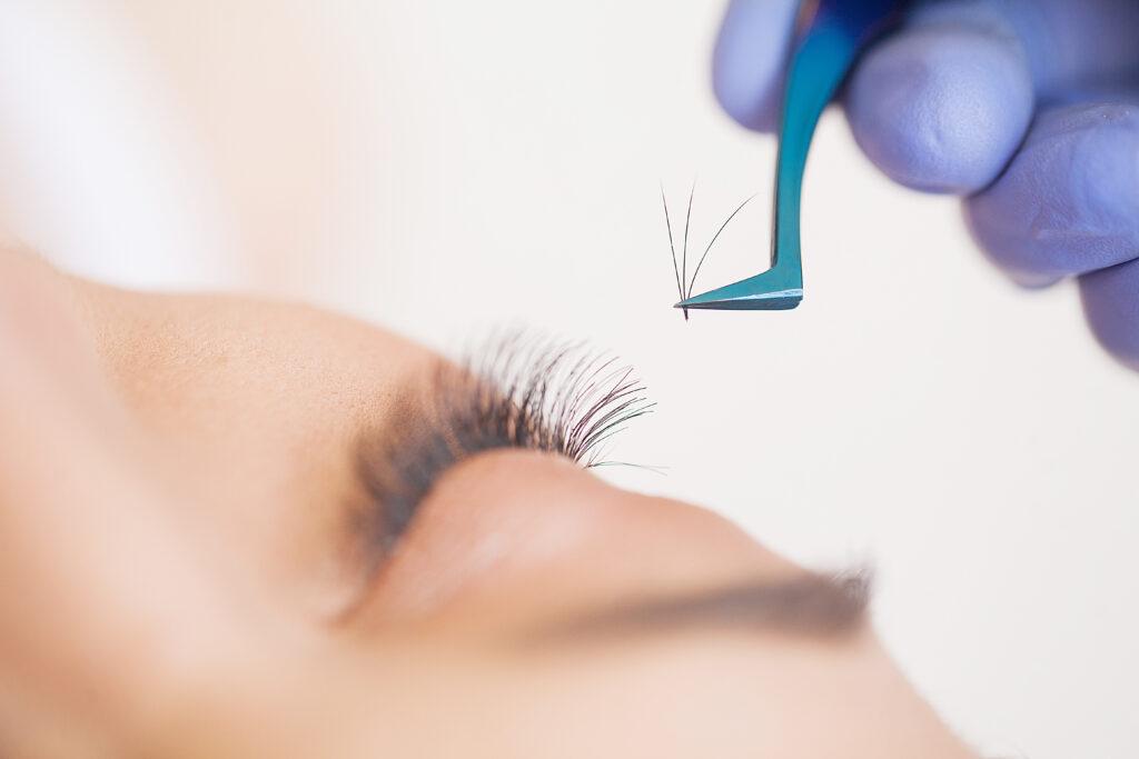 Eyelashes extensions. Fake Eyelashes. Eyelash Extension Procedure. Professional stylist lengthening female lashes. Master and a client in a beauty salon.